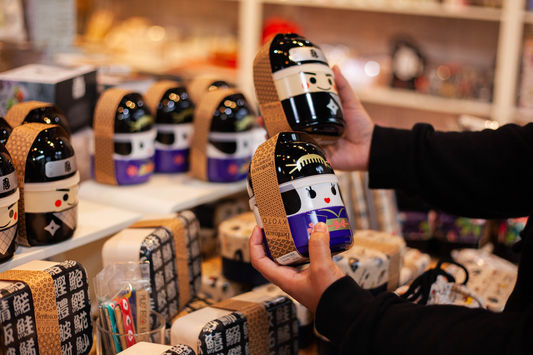 Person looking at a Kokeshi doll shaped bento box in a bento box shop
