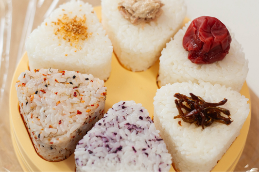 Six onigiri rice balls with various toppings on top of a plastic mold