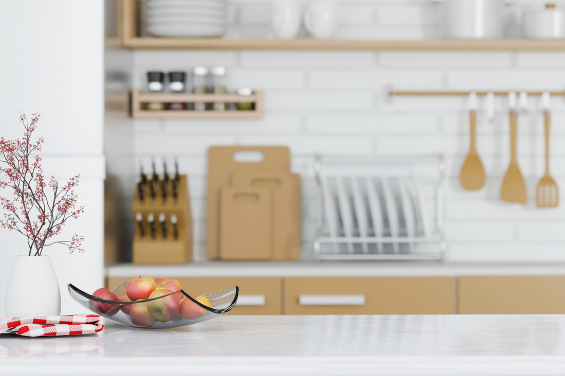 Kitchen interior with a bowl of fruits on the counter and utensils in the background