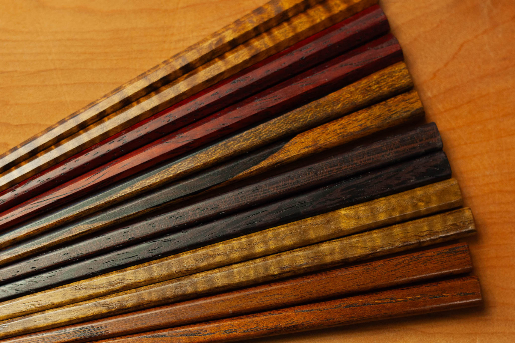 Several pairs of wooden chopsticks aligned on a wooden table