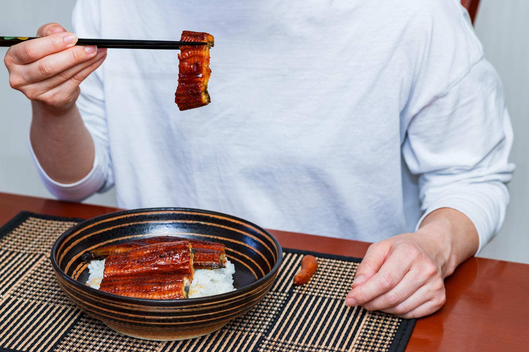 Person eating eel on rice at home