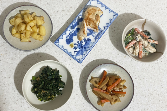 Assortment of Japanese side dishes in different plates on a white-grey counter