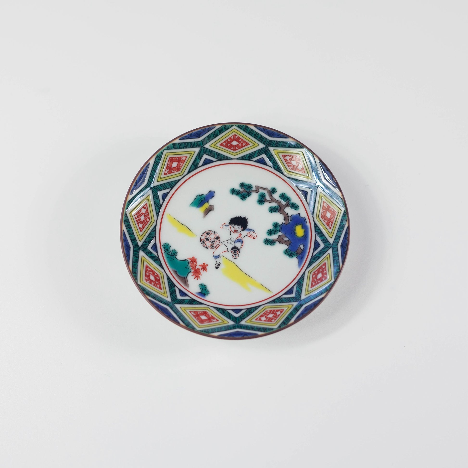 Decorative plate with geometric pattern and a cartoon character playing soccer in the center on a white background