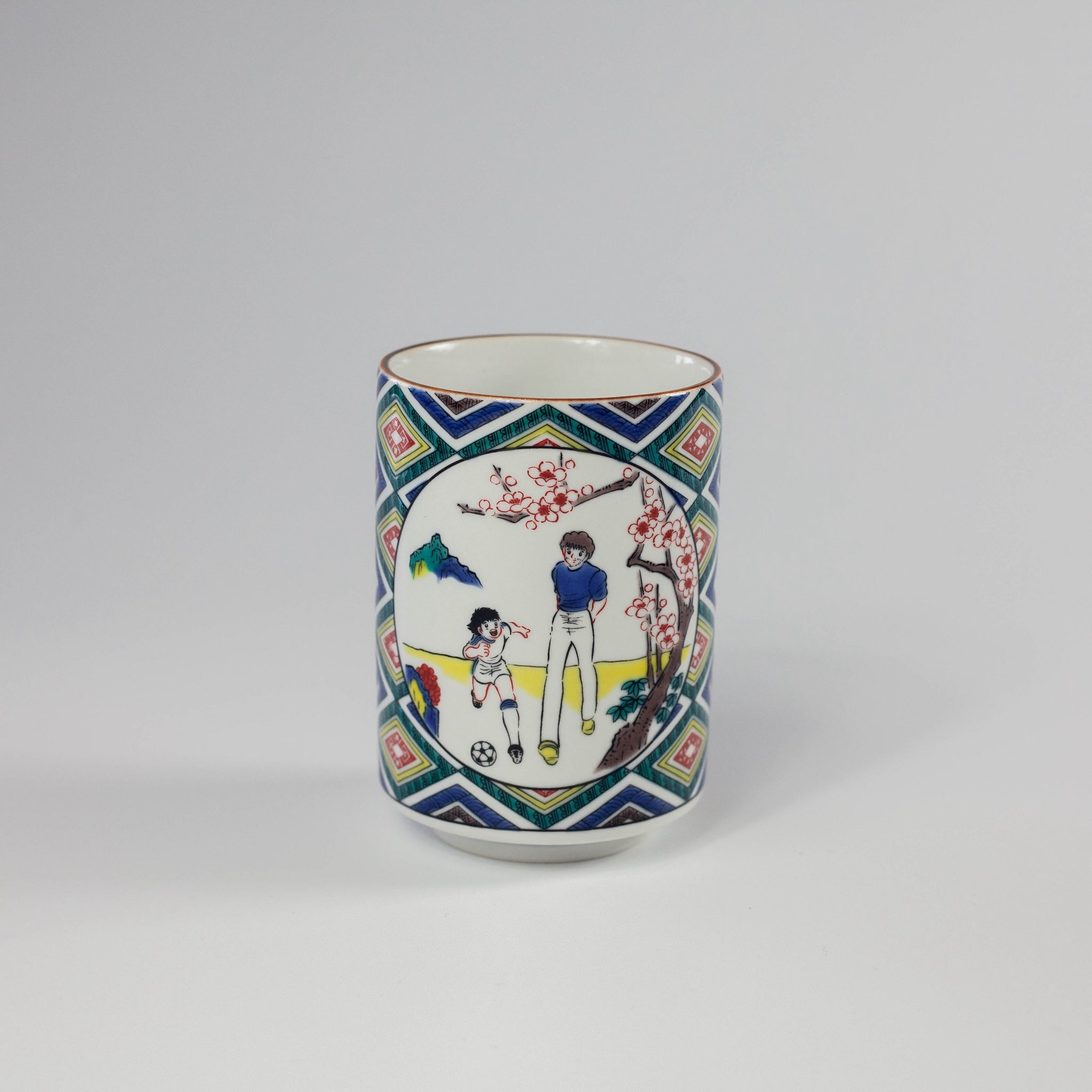 Decorative ceramic cup with colorful design of children playing soccer on a geometric patterned background.