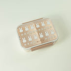 Pink lunch box with white bunny patterns on a light beige background