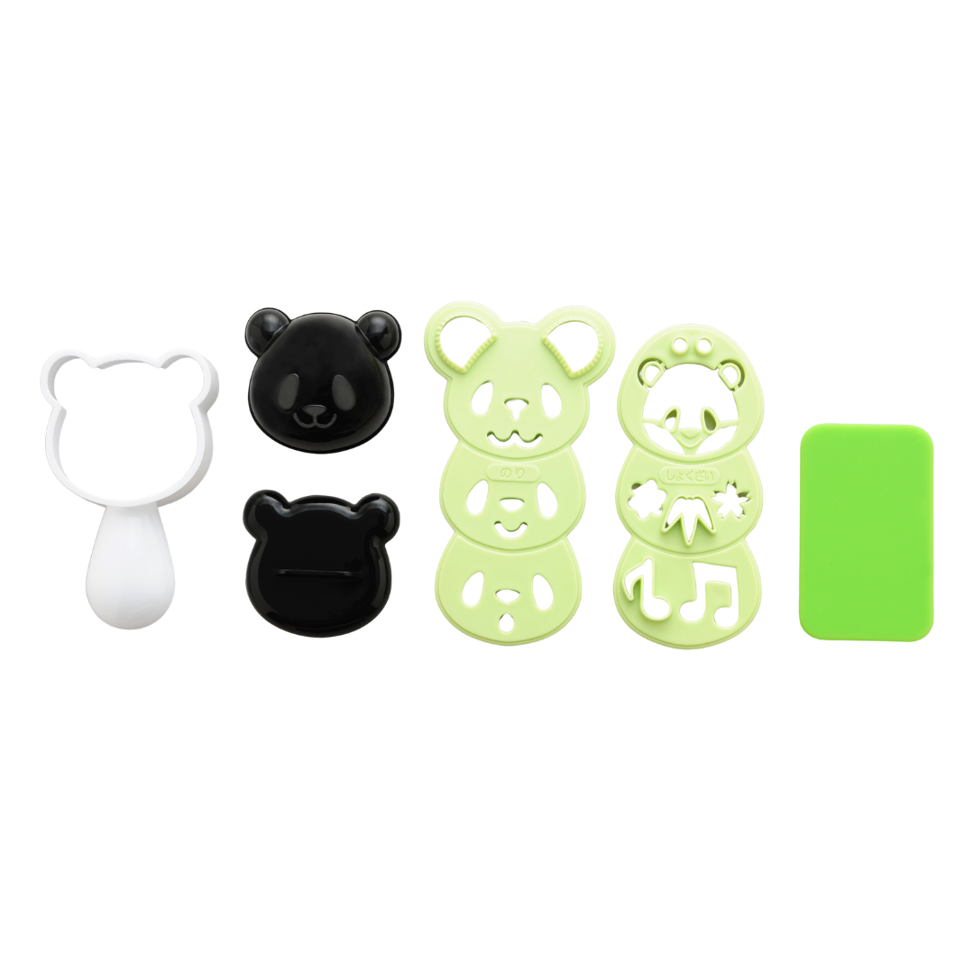Arnest Omusubi Panda Mold Set components laid out on white background – white panda-shaped rice mold with handle, two black panda face caps (smiling and winking), two green nori cutters with different face patterns, and a green rectangular cutting mat
