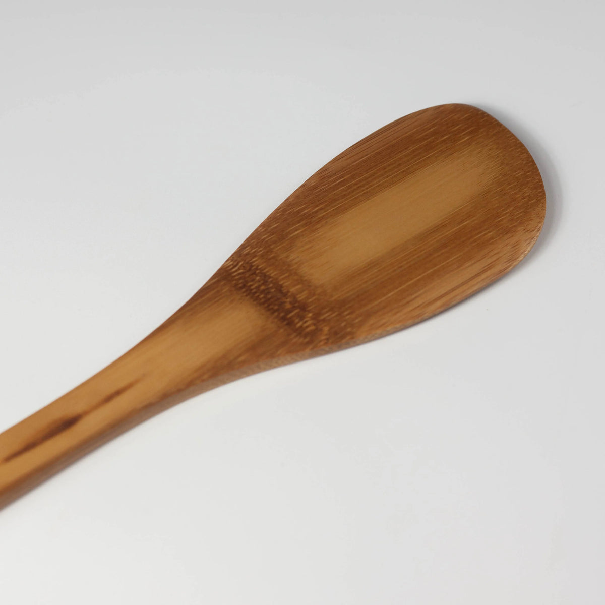 Close-up of the bamboo cooking spatula's broad rounded head and natural bamboo grain