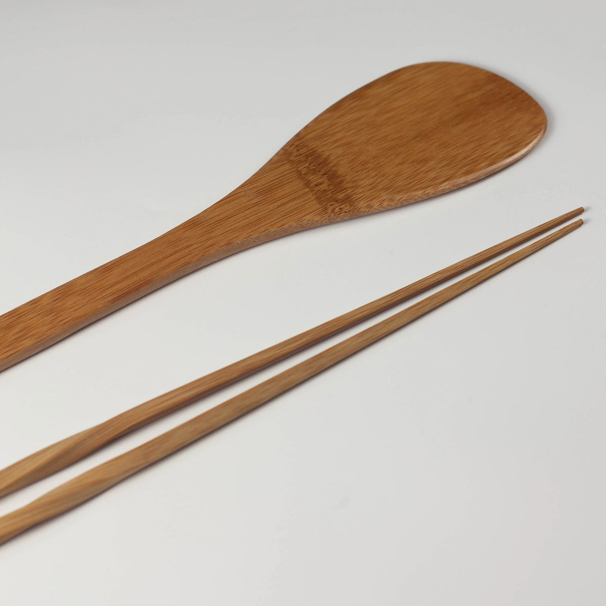  Bamboo cooking spatula shown from the reverse side beside long chopsticks with tapered tips